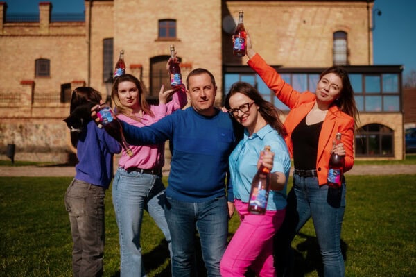 Evoto Grupa młodych ludzi z butelkami wina na tle winnicy i zamku, wino polskie.